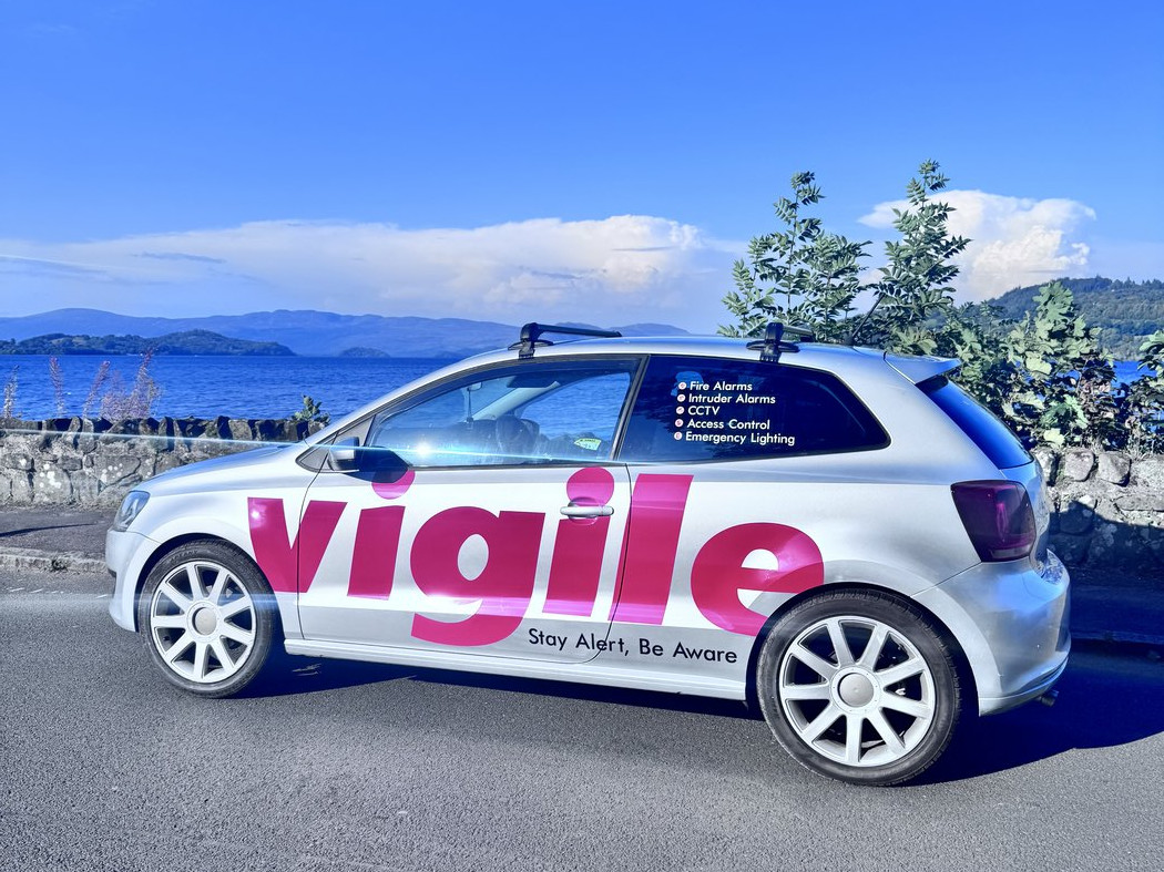 A Vigile Fire & Security branded van parked beside Loch Lomond, showing the fire alarm, intruder alarm, CCTV, access control and emergency lighting services offered